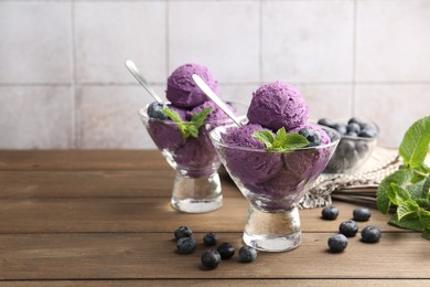 Photo of Tasty sorbet with blueberries and mint in dessert bowls on wooden table against tiled background, closeup