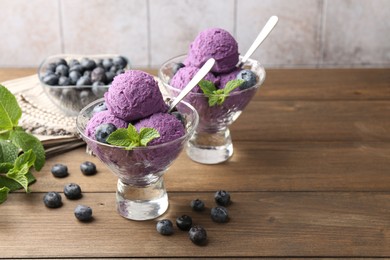 Photo of Tasty sorbet with blueberries and mint in dessert bowls on wooden table, closeup