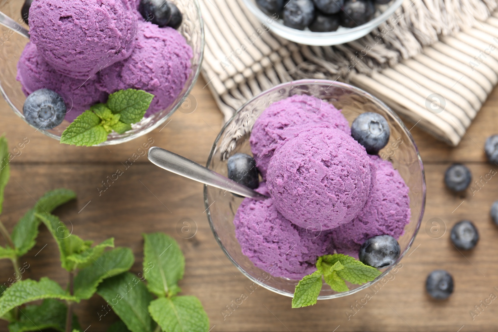 Tasty sorbet with blueberries and mint in dessert bowls on wooden table, flat lay Photo of Tasty sorbet with blueberries and mint in dessert bowls on wooden table, flat lay