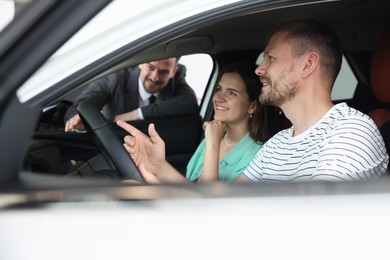 Photo of Salesman showing new car to happy family, selective focus