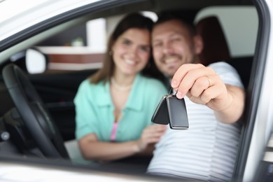 Photo of Happy family with keys inside new car, selective focus