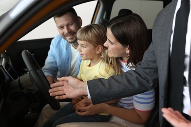 Photo of Salesman showing new car to happy family, closeup