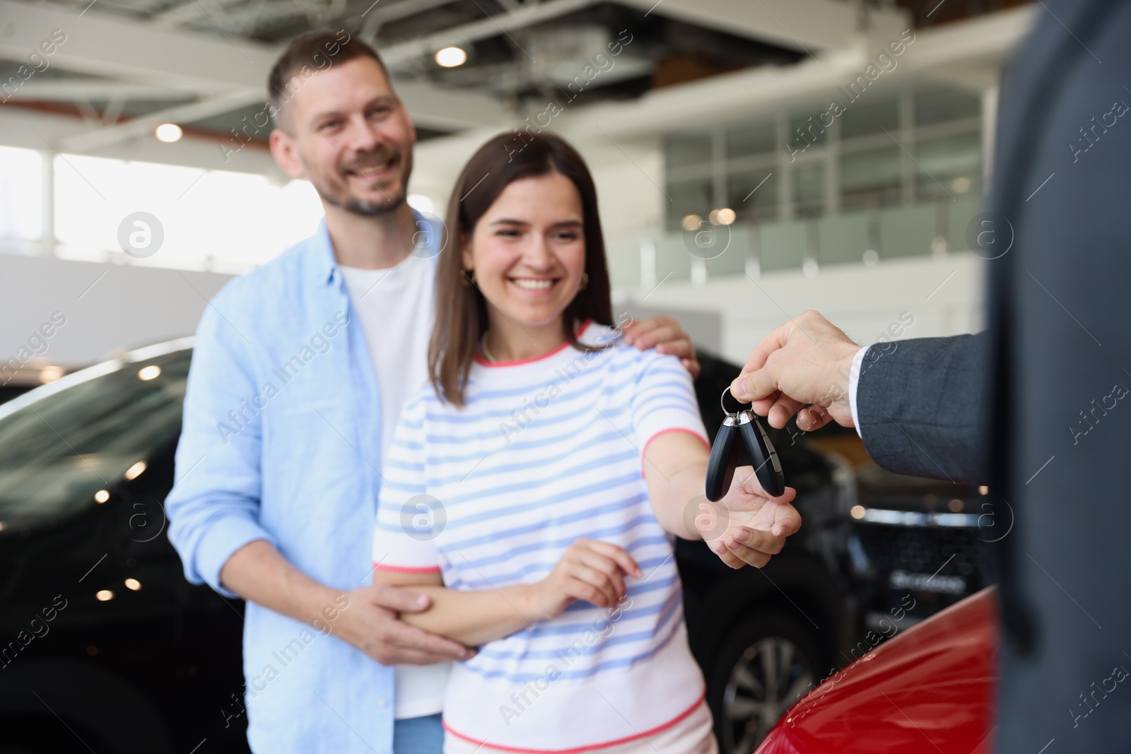 Photo of Salesman giving car key to happy family in salon, selective focus