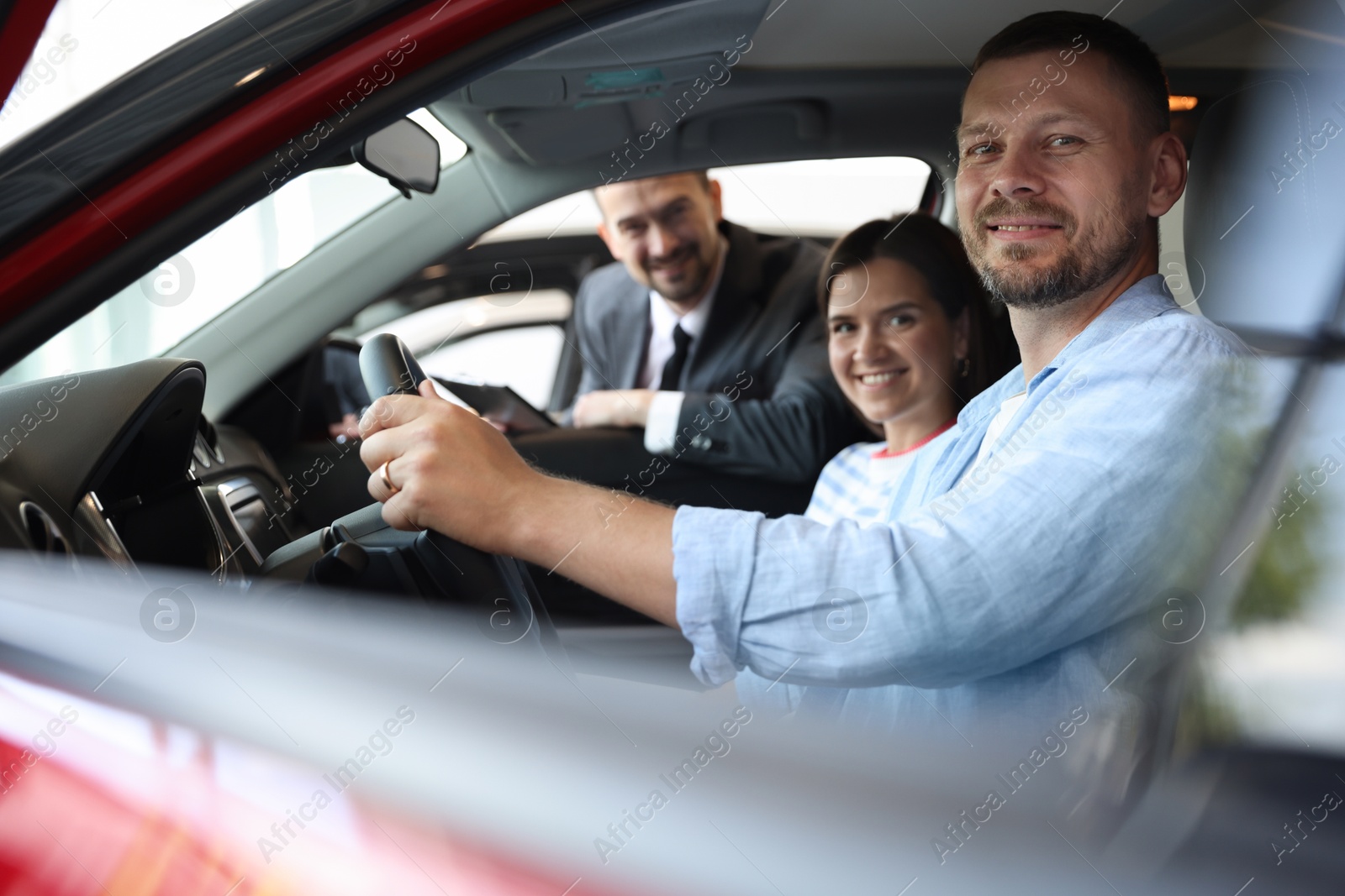Salesman showing new car to happy family, selective focus Photo of Salesman showing new car to happy family, selective focus