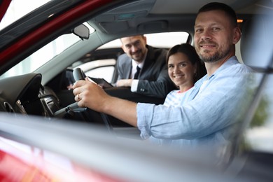 Photo of Salesman showing new car to happy family, selective focus