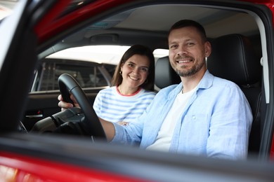 Photo of Happy family sitting inside new car. Luxury vehicle