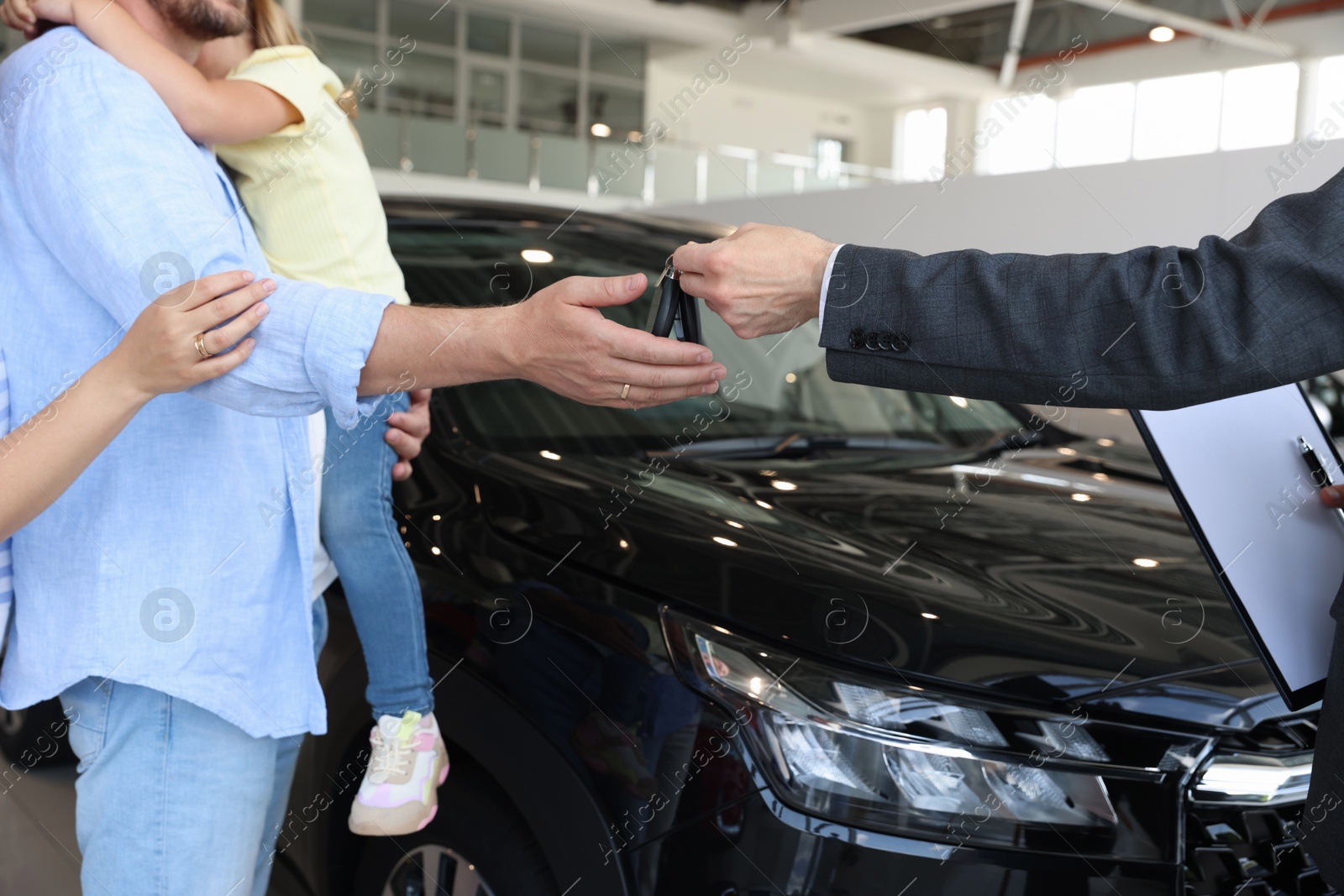 Photo of Salesman giving car key to family in salon, closeup