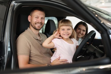 Photo of Happy family sitting inside new car. Luxury vehicle