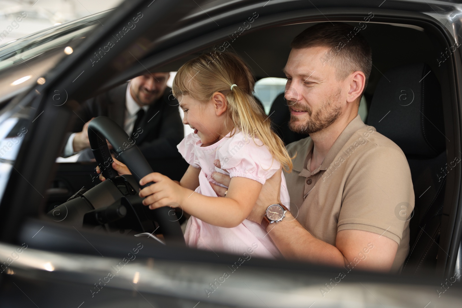 Happy family holding steering wheel inside new car and salesman, selective focus Photo of Happy family holding steering wheel inside new car and salesman, selective focus