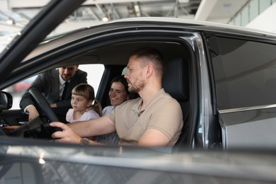 Photo of Happy family inside new car and salesman, selective focus