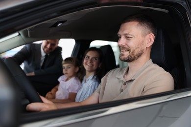 Photo of Happy family inside new car and salesman, selective focus