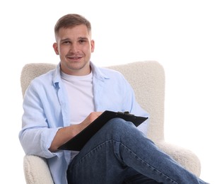 Photo of Smiling psychologist with clipboard sitting on armchair against white background