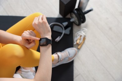 Photo of Woman checking fitness tracker during training indoors, above view. Space for text