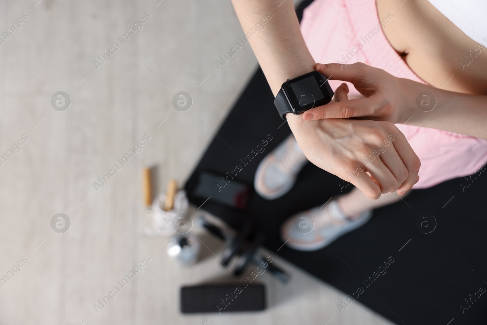 Photo of Woman checking fitness tracker during training indoors, above view. Space for text