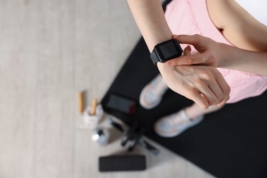 Photo of Woman checking fitness tracker during training indoors, above view. Space for text
