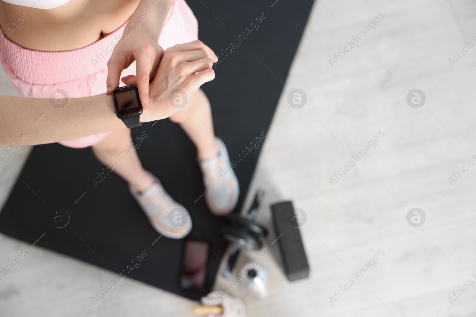 Photo of Woman checking fitness tracker during training indoors, above view. Space for text