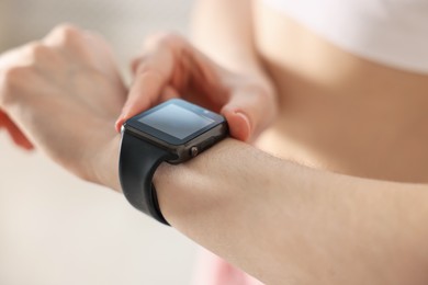 Photo of Woman checking fitness tracker during training indoors, closeup