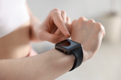 Photo of Woman checking fitness tracker during training indoors, closeup