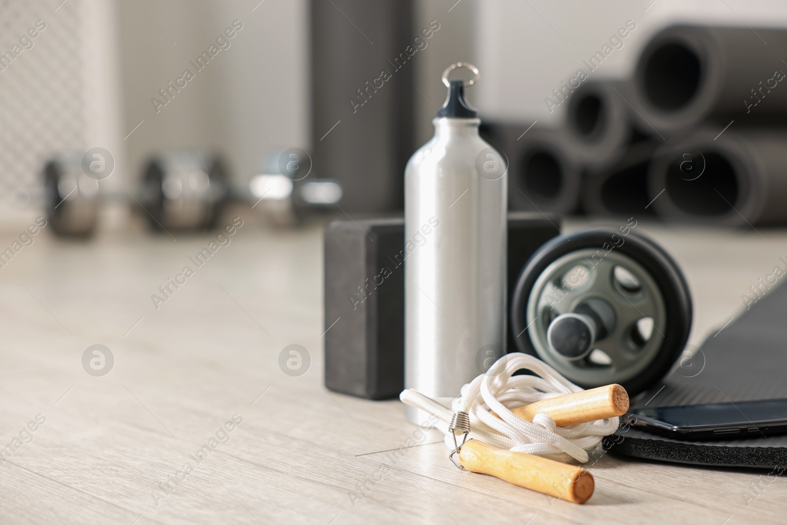 Phone and different fitness equipment on floor in gym, closeup. Space for text Photo of Phone and different fitness equipment on floor in gym, closeup. Space for text