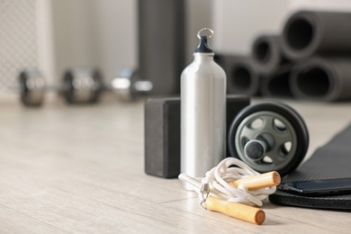 Photo of Phone and different fitness equipment on floor in gym, closeup. Space for text