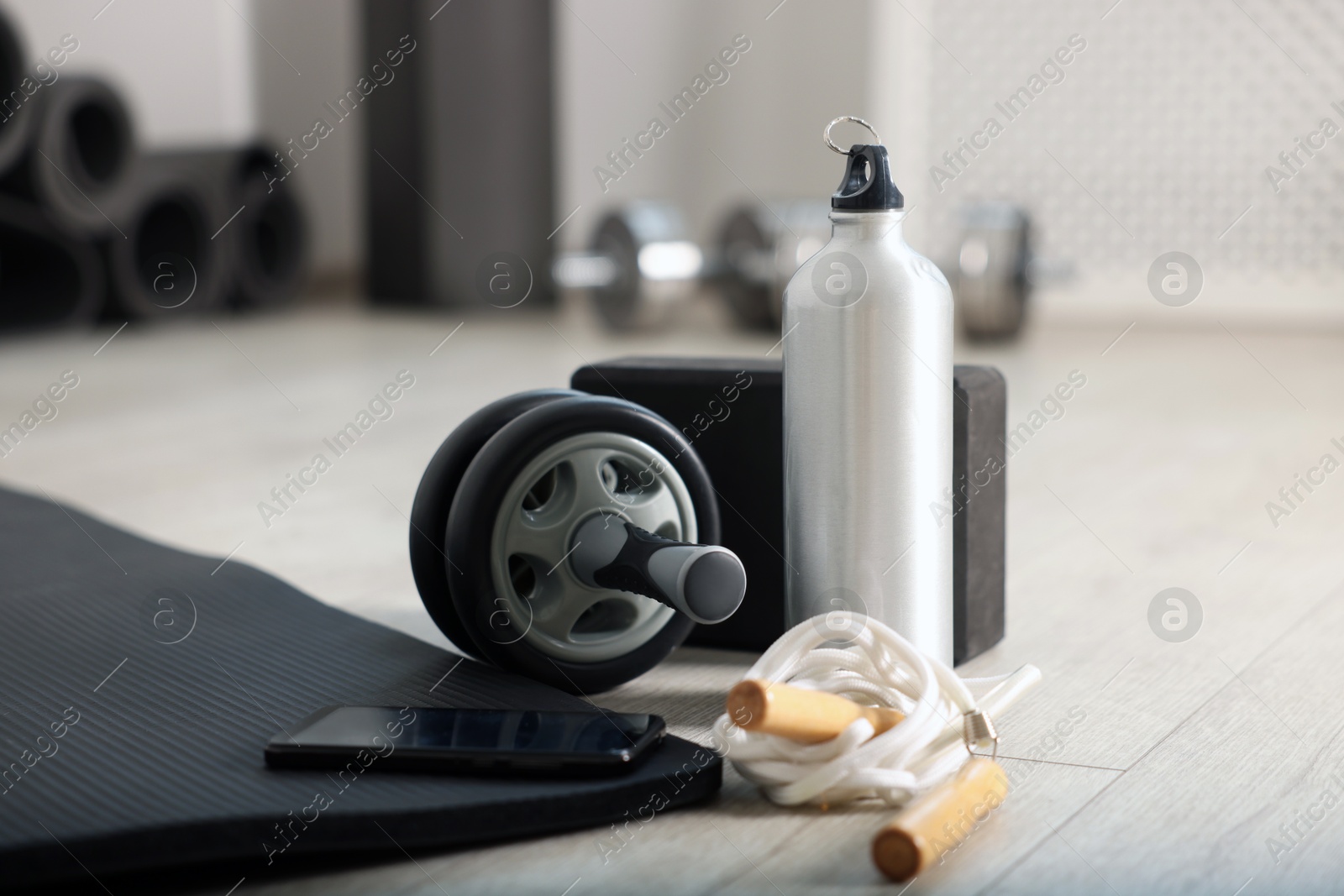 Phone and different fitness equipment on floor in gym, closeup Photo of Phone and different fitness equipment on floor in gym, closeup