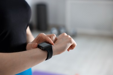 Photo of Woman checking fitness tracker during training indoors, closeup. Space for text