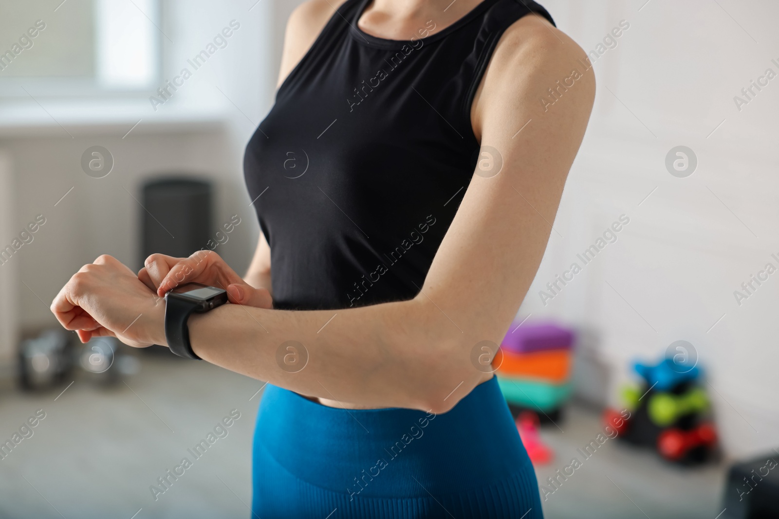 Woman checking fitness tracker during training indoors, closeup Photo of Woman checking fitness tracker during training indoors, closeup