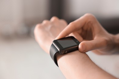 Photo of Woman checking fitness tracker during training indoors, closeup