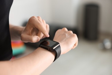 Photo of Woman checking fitness tracker during training indoors, closeup. Space for text
