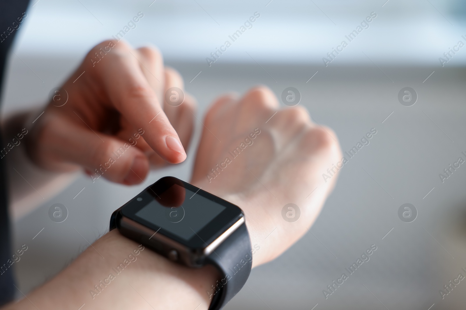 Photo of Woman checking fitness tracker during training indoors, closeup