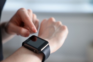 Photo of Woman checking fitness tracker during training indoors, closeup