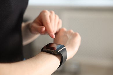 Photo of Woman checking fitness tracker during training indoors, closeup. Space for text