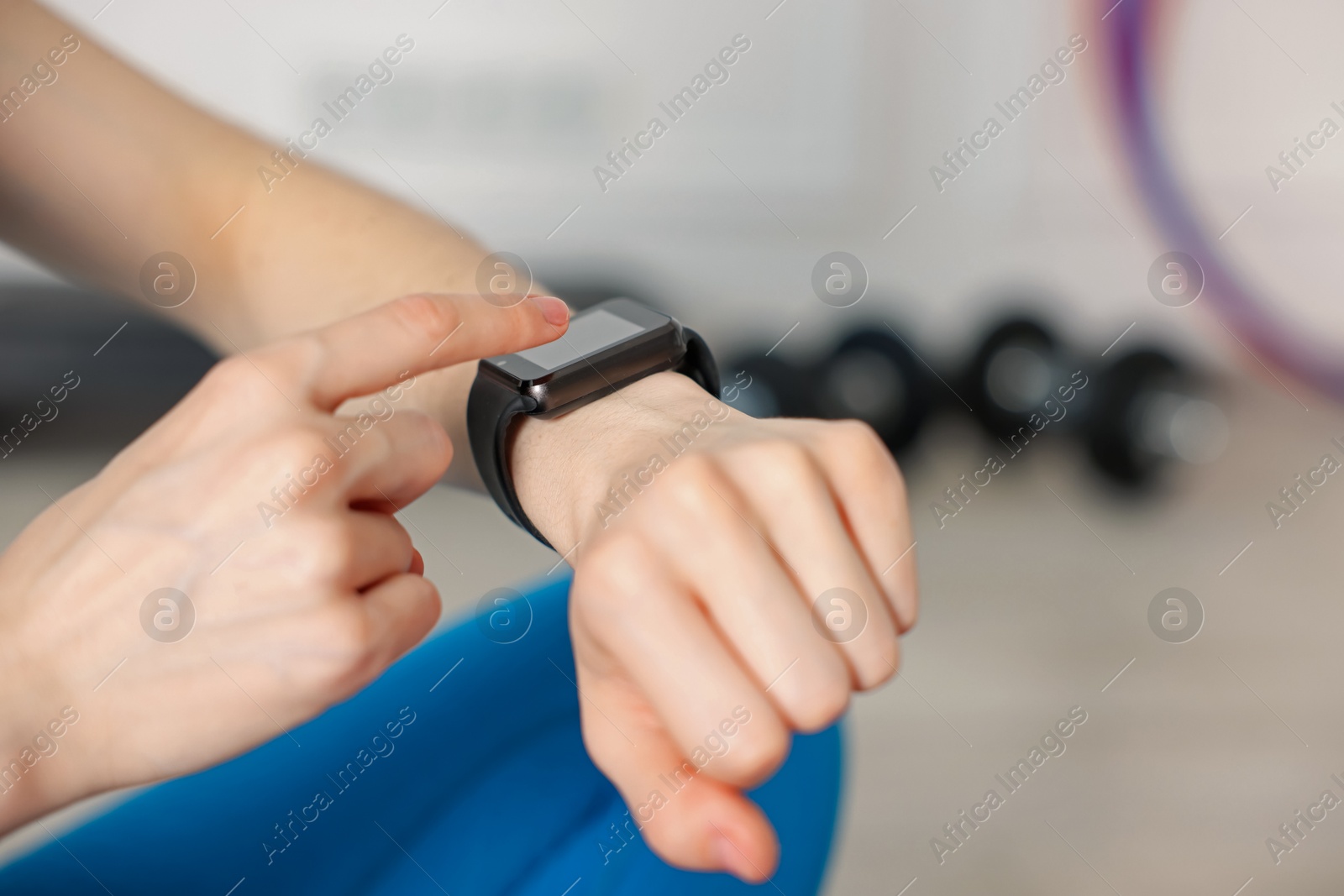 Woman checking fitness tracker during training indoors, closeup. Space for text Photo of Woman checking fitness tracker during training indoors, closeup. Space for text