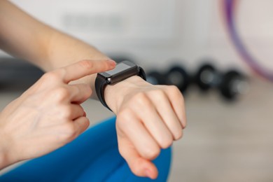 Photo of Woman checking fitness tracker during training indoors, closeup. Space for text
