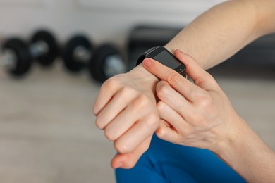 Photo of Woman checking fitness tracker during training indoors, closeup. Space for text