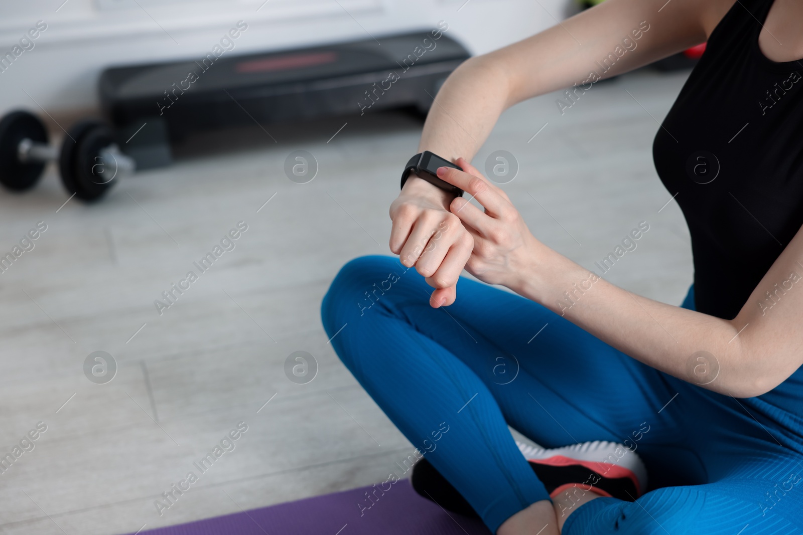 Woman checking fitness tracker during training indoors, closeup. Space for text Photo of Woman checking fitness tracker during training indoors, closeup. Space for text