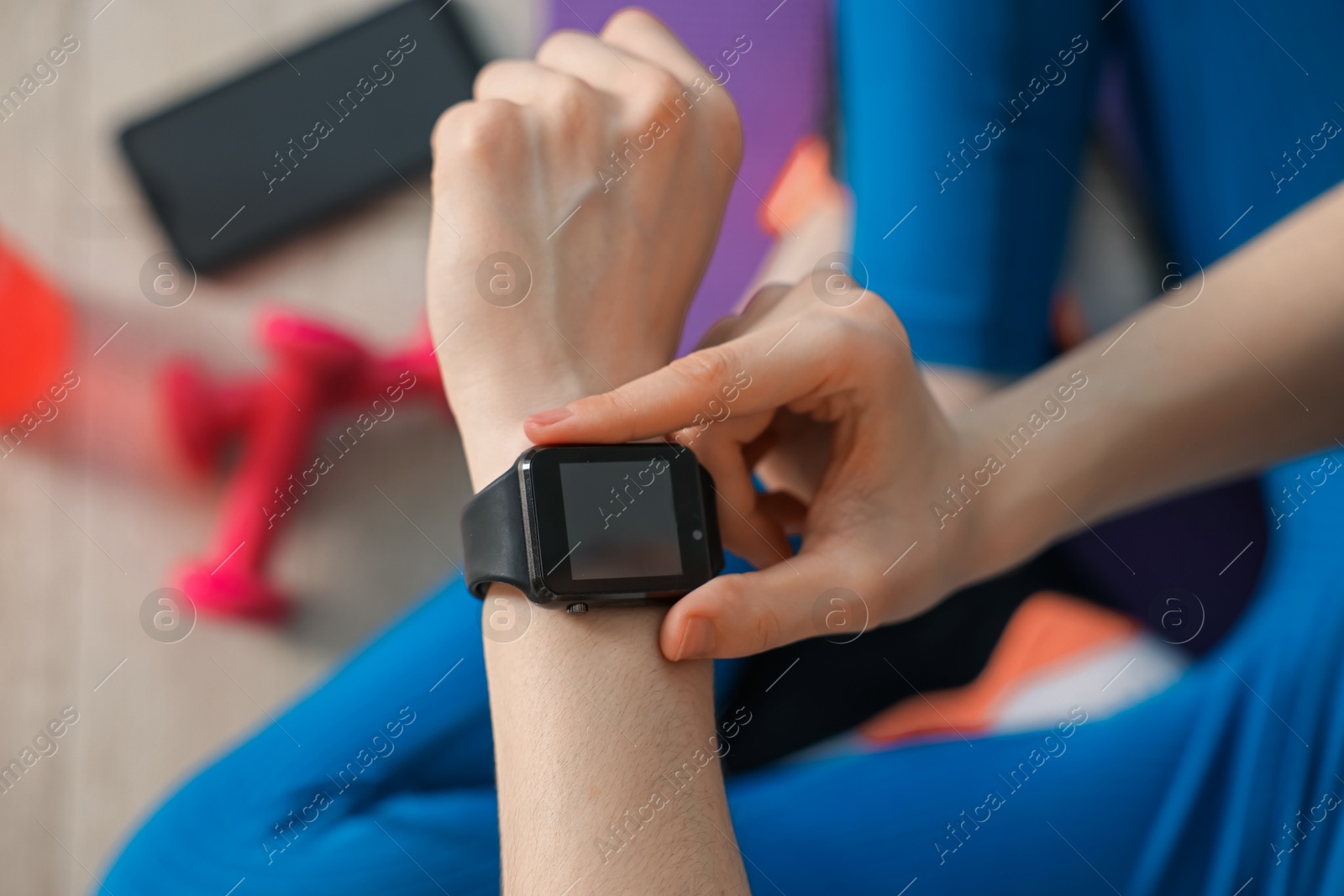 Woman checking fitness tracker during training indoors, closeup Photo of Woman checking fitness tracker during training indoors, closeup