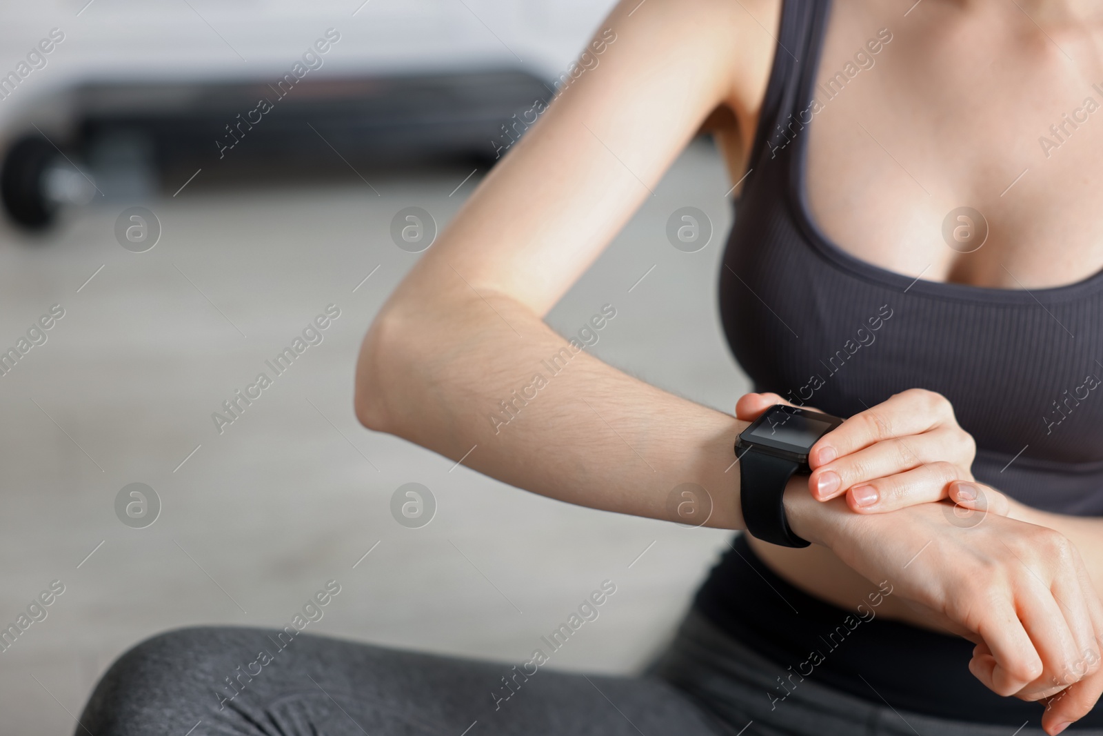 Woman checking fitness tracker during training indoors, closeup Photo of Woman checking fitness tracker during training indoors, closeup
