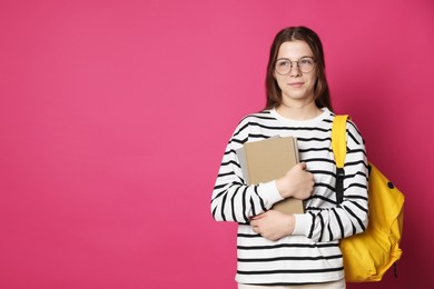 Photo of Teenage girl in glasses with backpack and books on crimson background, space for text
