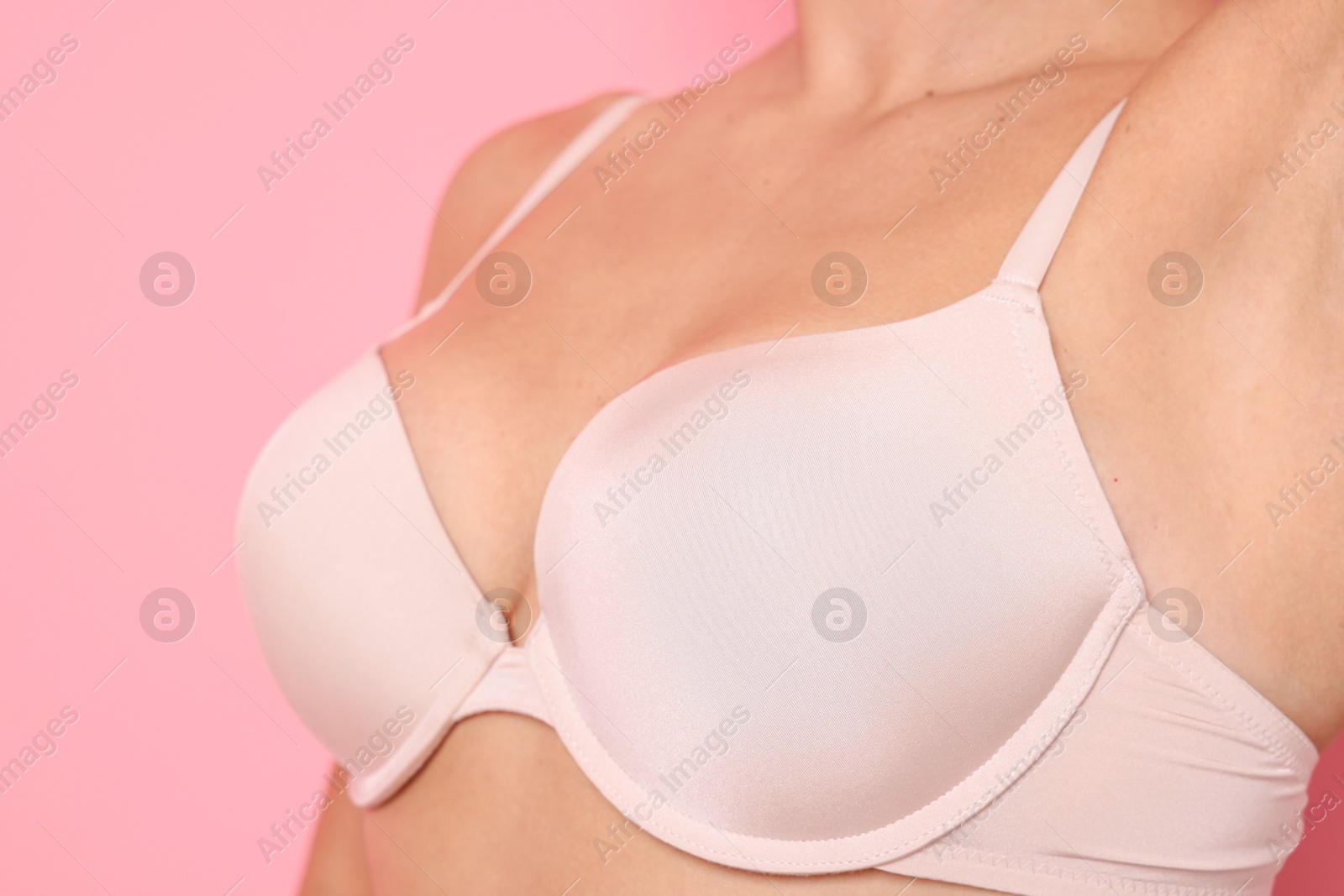 Woman wearing beautiful beige bra on pink background, closeup Photo of Woman wearing beautiful beige bra on pink background, closeup