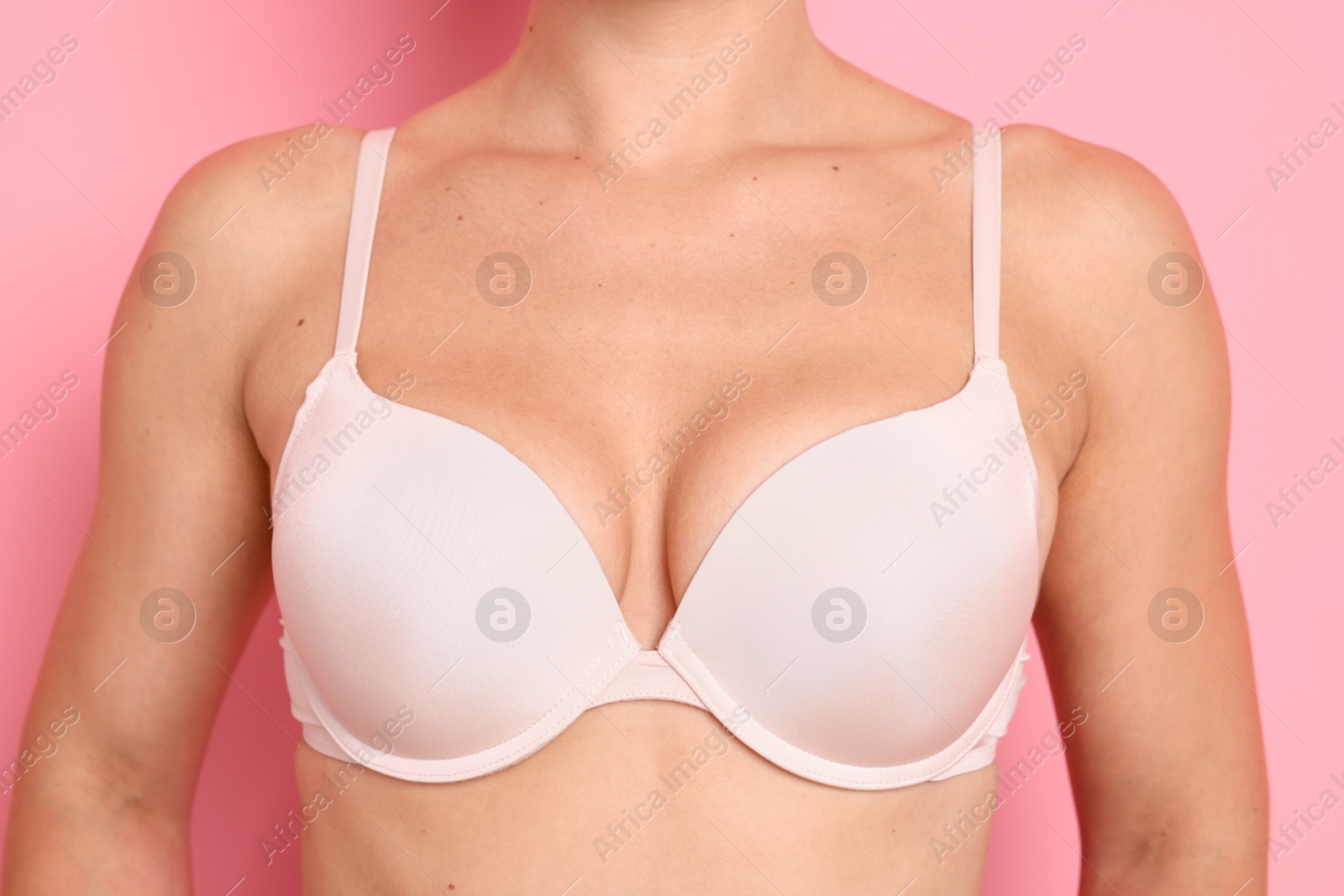 Woman wearing beautiful beige bra on pink background, closeup Photo of Woman wearing beautiful beige bra on pink background, closeup