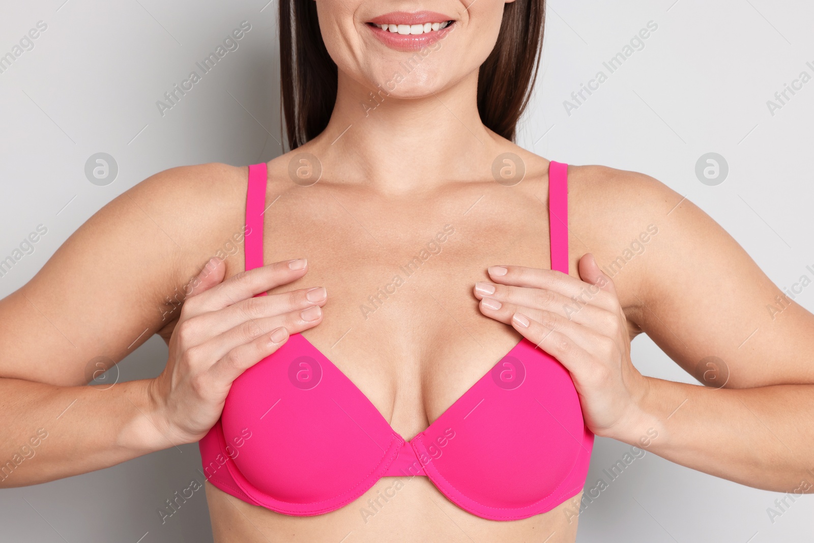 Woman wearing beautiful pink bra on light grey background, closeup Photo of Woman wearing beautiful pink bra on light grey background, closeup