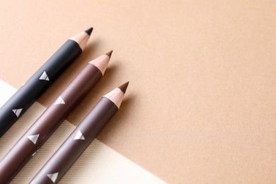 Photo of Different eyebrow pencils on beige background, flat lay. Space for text