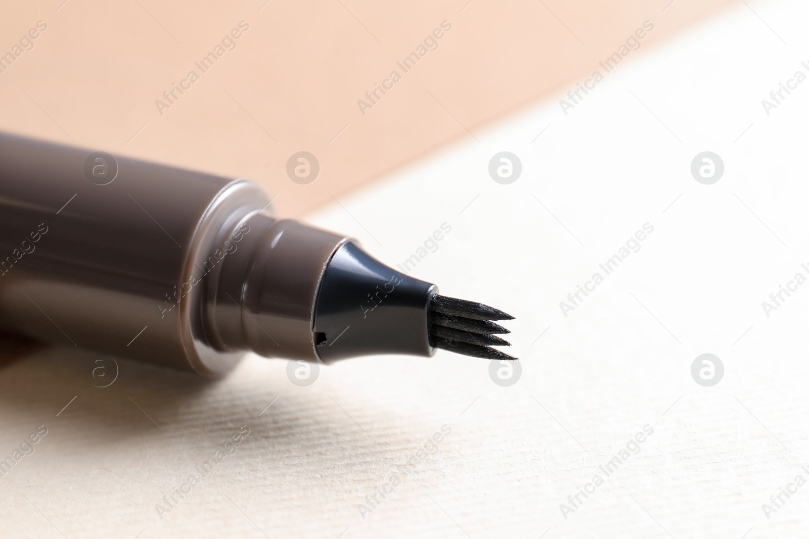 Brown liquid eyebrow pencil on beige background, closeup. Space for text Photo of Brown liquid eyebrow pencil on beige background, closeup. Space for text
