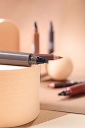 Photo of Stylish presentation of liquid eyebrow pencils on beige background, closeup