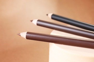 Photo of Different eyebrow pencils on beige background, closeup