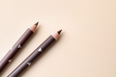 Photo of Different eyebrow pencils on beige background, top view. Space for text