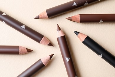 Photo of Different eyebrow pencils on beige background, flat lay