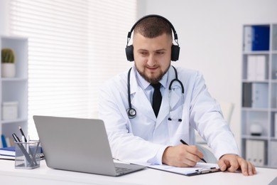 Photo of Doctor in headphones having online consultation via laptop indoors