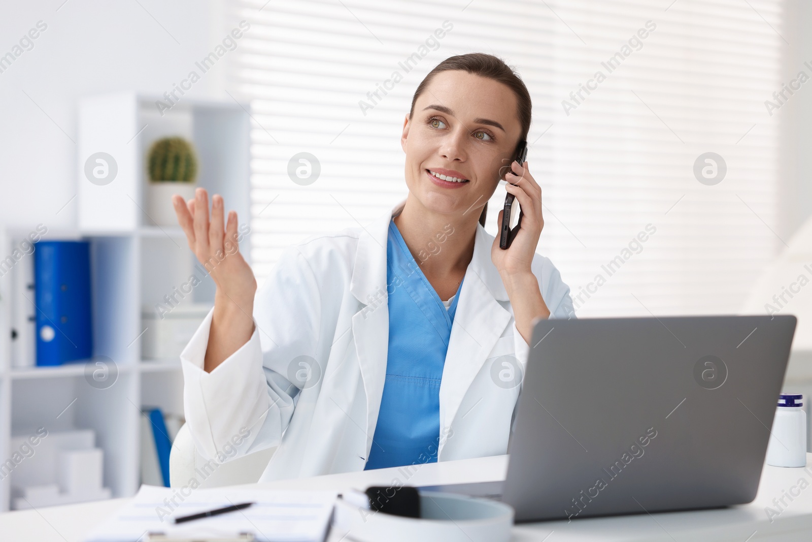 Doctor with smartphone having online consultation in clinic Photo of Doctor with smartphone having online consultation in clinic